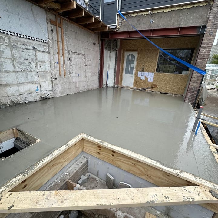 Vers gestorte betonvloer voor een uitbouw achter een woning, met de bekisting er nog omheen, werk in uitvoering